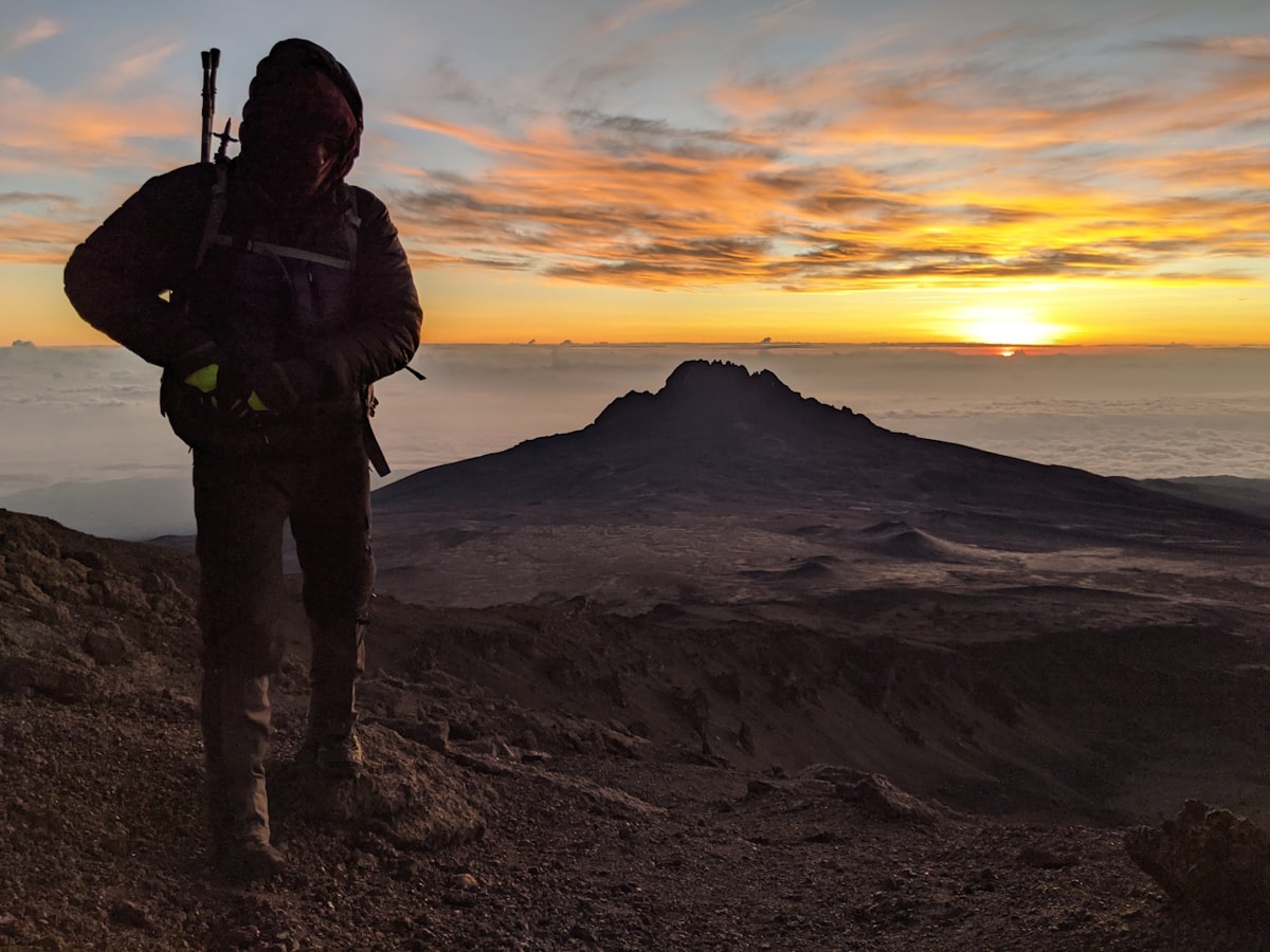 Climber silhouette at Kilimanjaro summit with Mawenzi peak